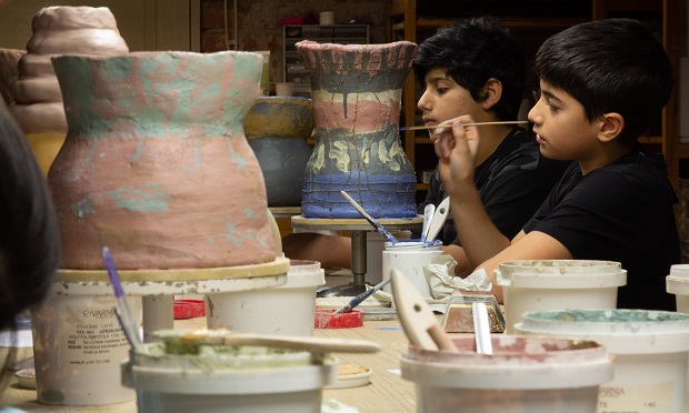 Two boys decorate ceramic vases