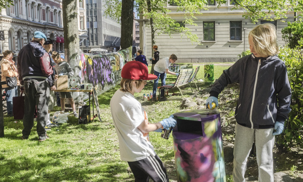 Two children and an adult in the background doing art activities in Annantalo's yard during summer